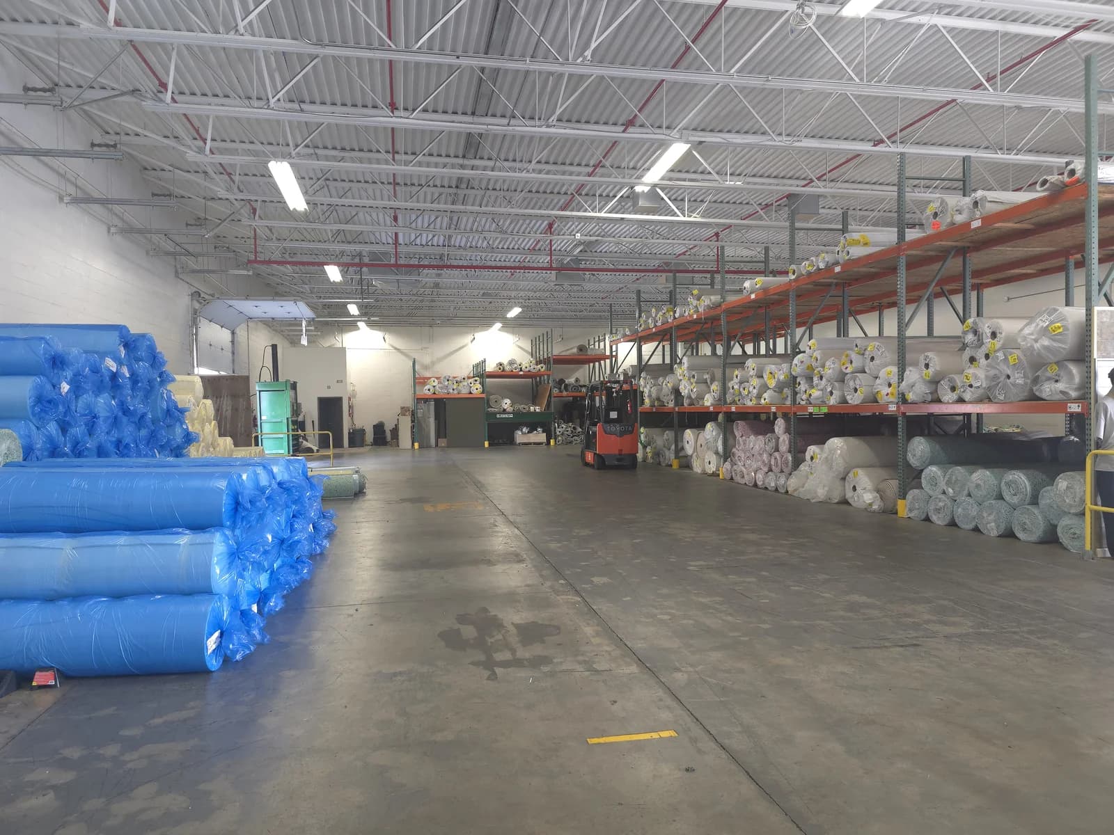 Carpet and padding rolls staged in the Next Step Flooring warehouse